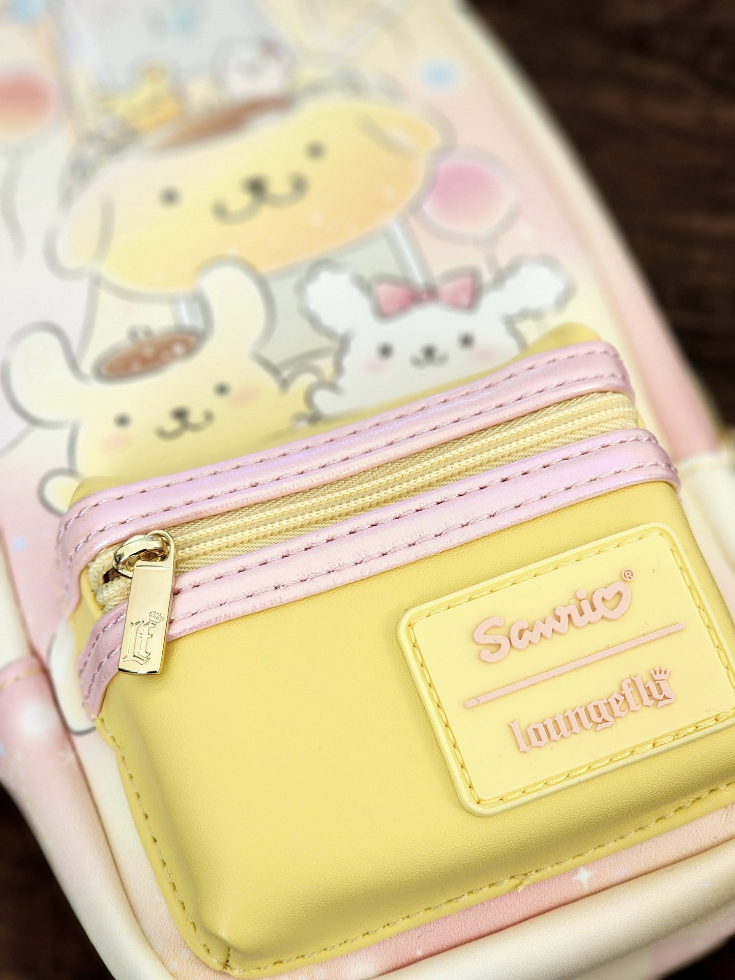 Yellow pouch with pink zipper and cartoon character design on a phone case.