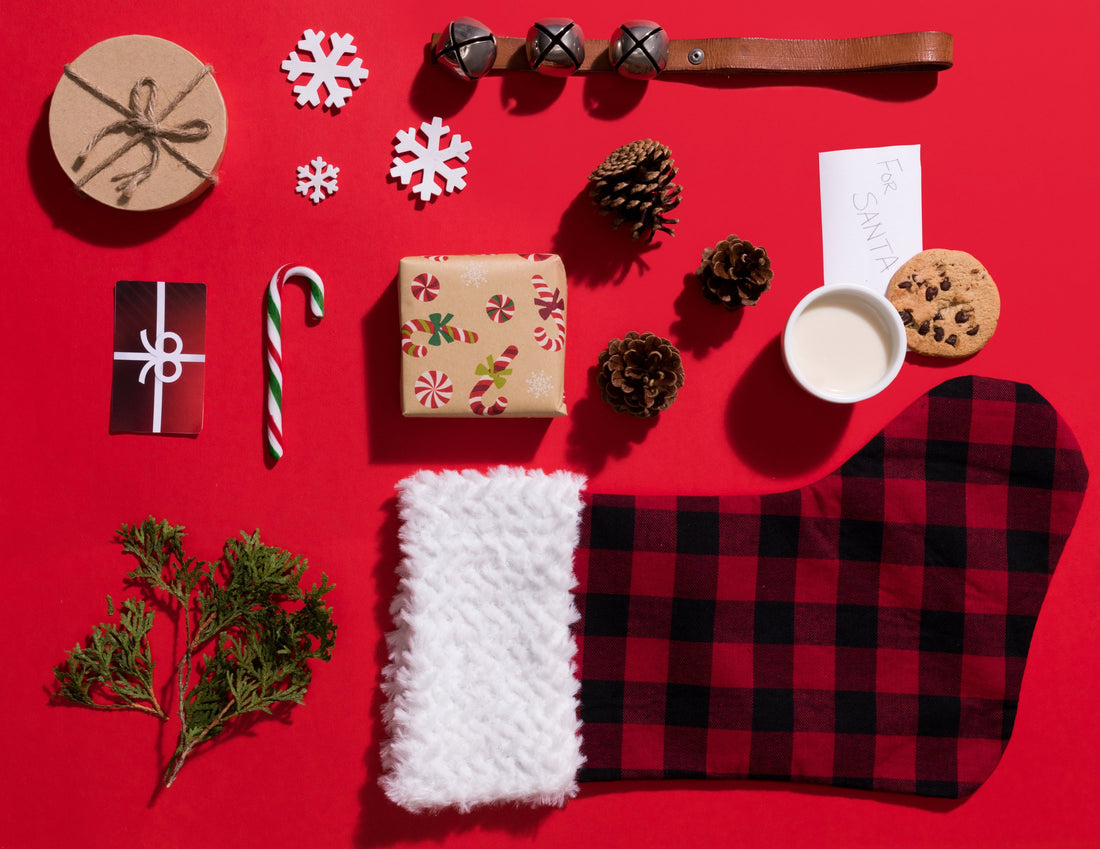 Holiday Christmas Theme Flatlay Red Background with Plaid Stocking Candy Cane Pine Cones Bells