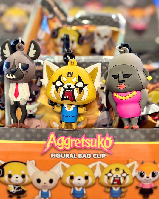 Aggretsuko figurine bag clips with a colorful background featuring the Aggretsuko logo.
