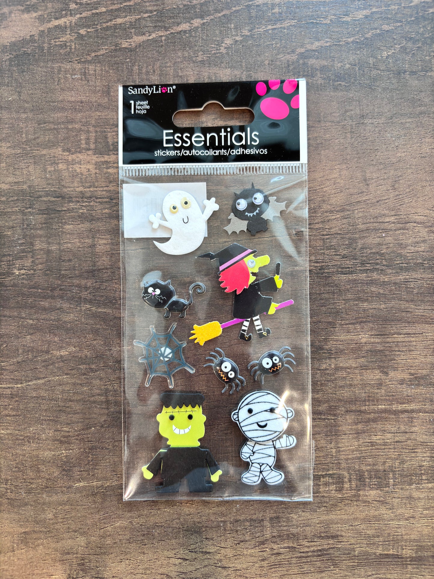 Sandy Lion Essentials Halloween-themed adhesive patch pack containing 11 different patches, displayed on a dark wood background.