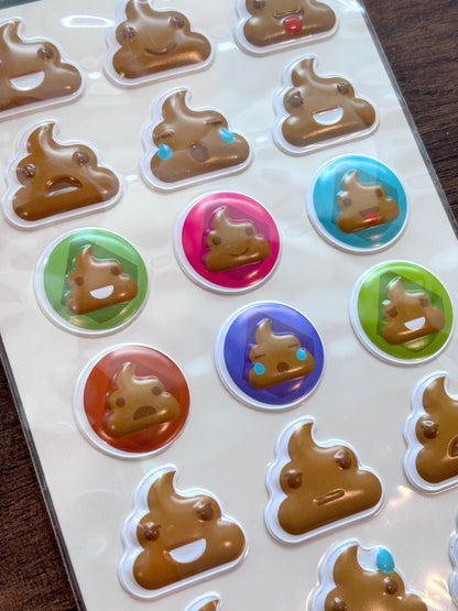 A close-up of a sheet of stickers featuring cartoon poop emoji designs in various colors, including brown, blue, green, pink, and orange, on a white backing.