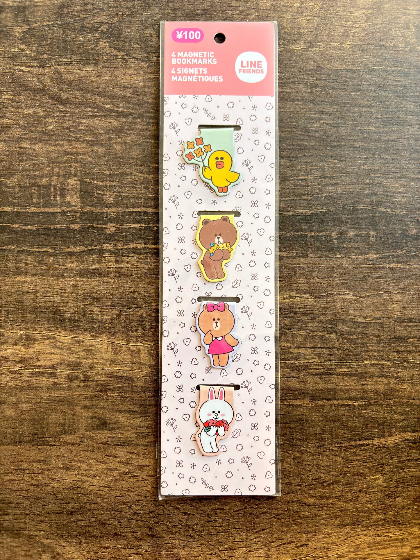 Pack of magnetic clips with cartoon characters on a wooden surface
