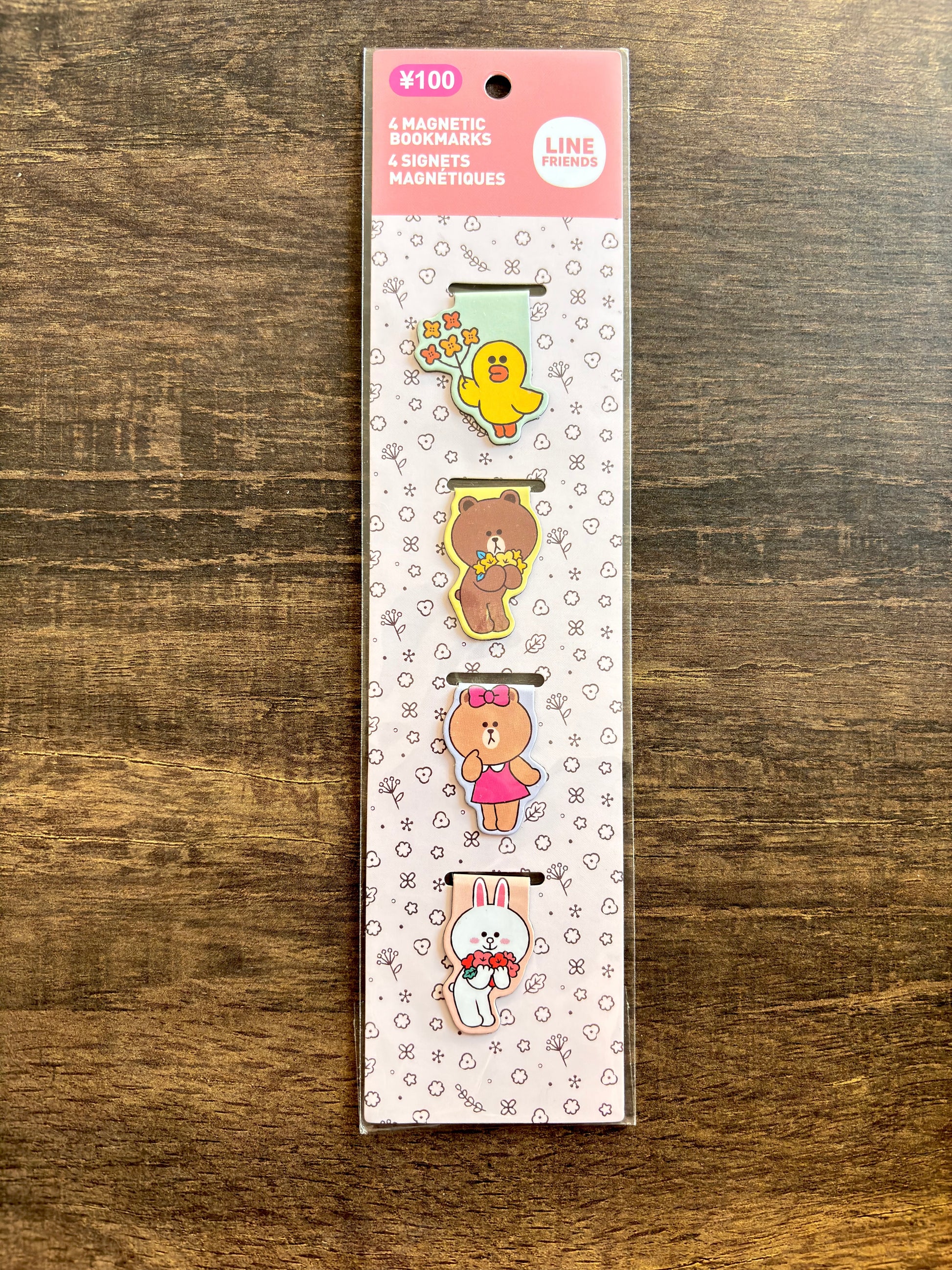 Pack of magnetic clips with cartoon characters on a wooden surface