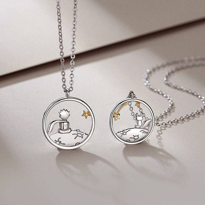 Two silver necklaces from The Little Prince with circular pendants on a light surface