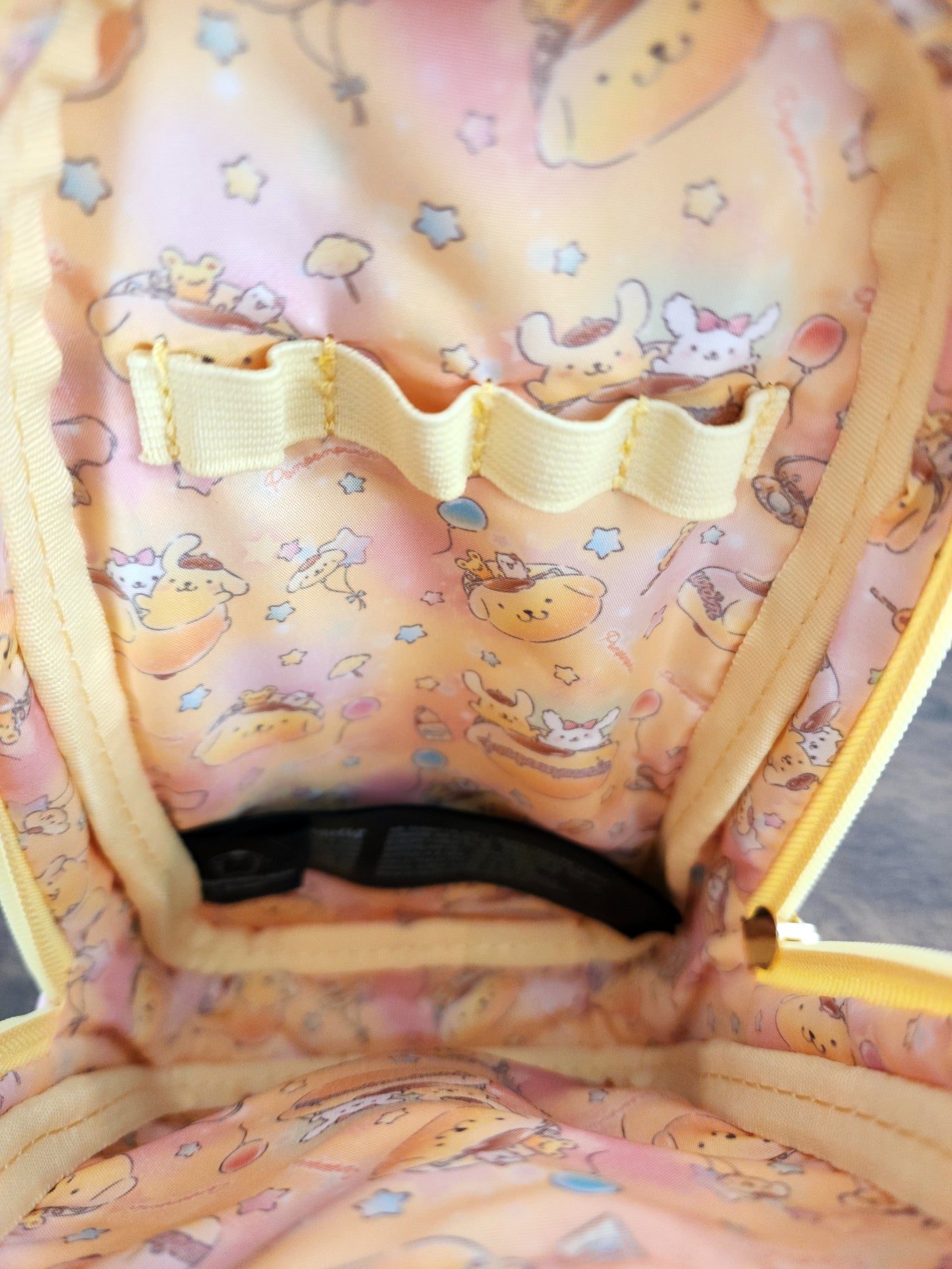 Close-up of a pencil/pen bag with cartoon designs and a yellow strap.