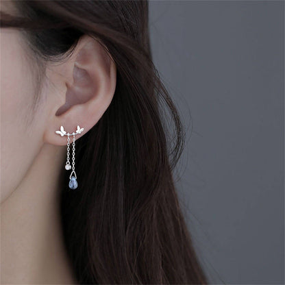 Close-up of an ear wearing a delicate earring with a gray background
