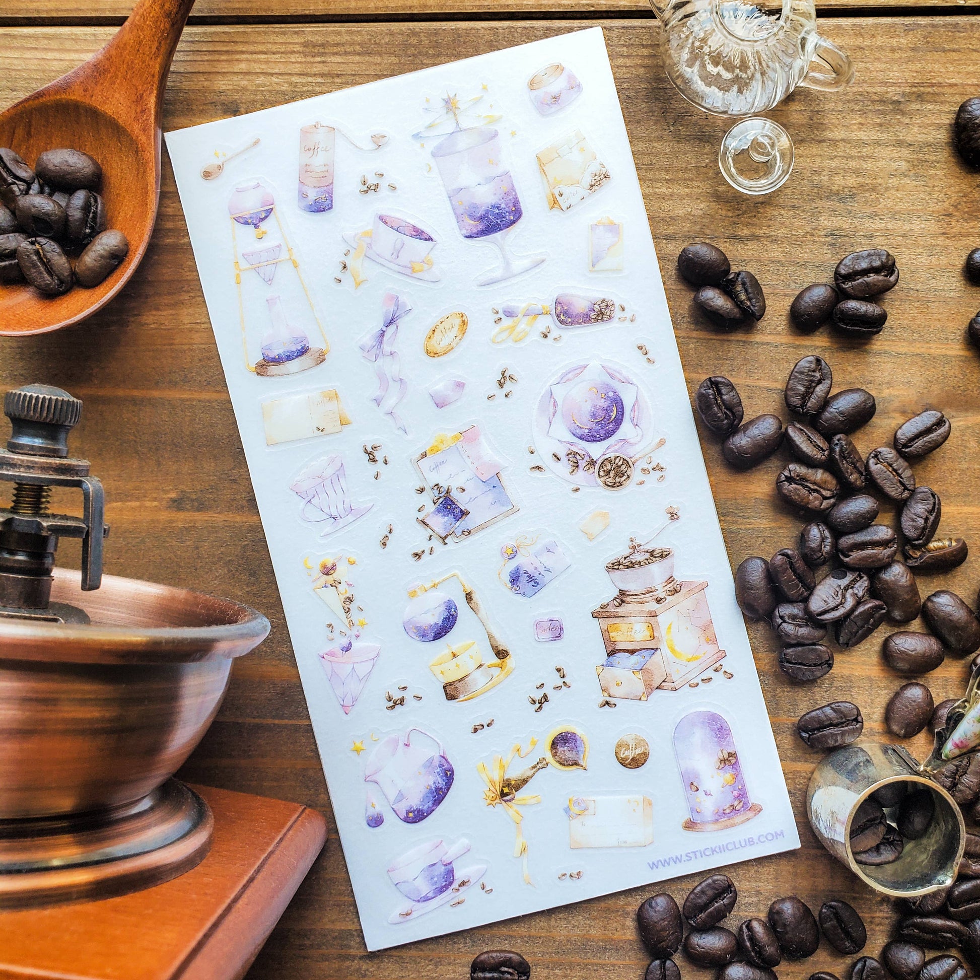 Sheet of decorative stickers with coffee-themed designs on a wooden surface with coffee beans and a grinder.