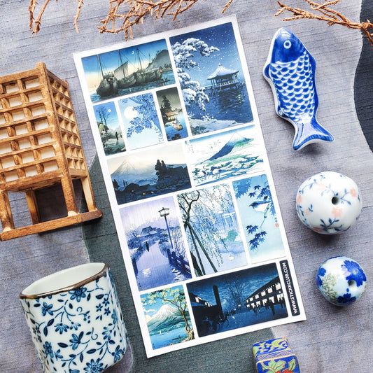 Set of blue and white illustrated postcards on a textured surface with decorative items.