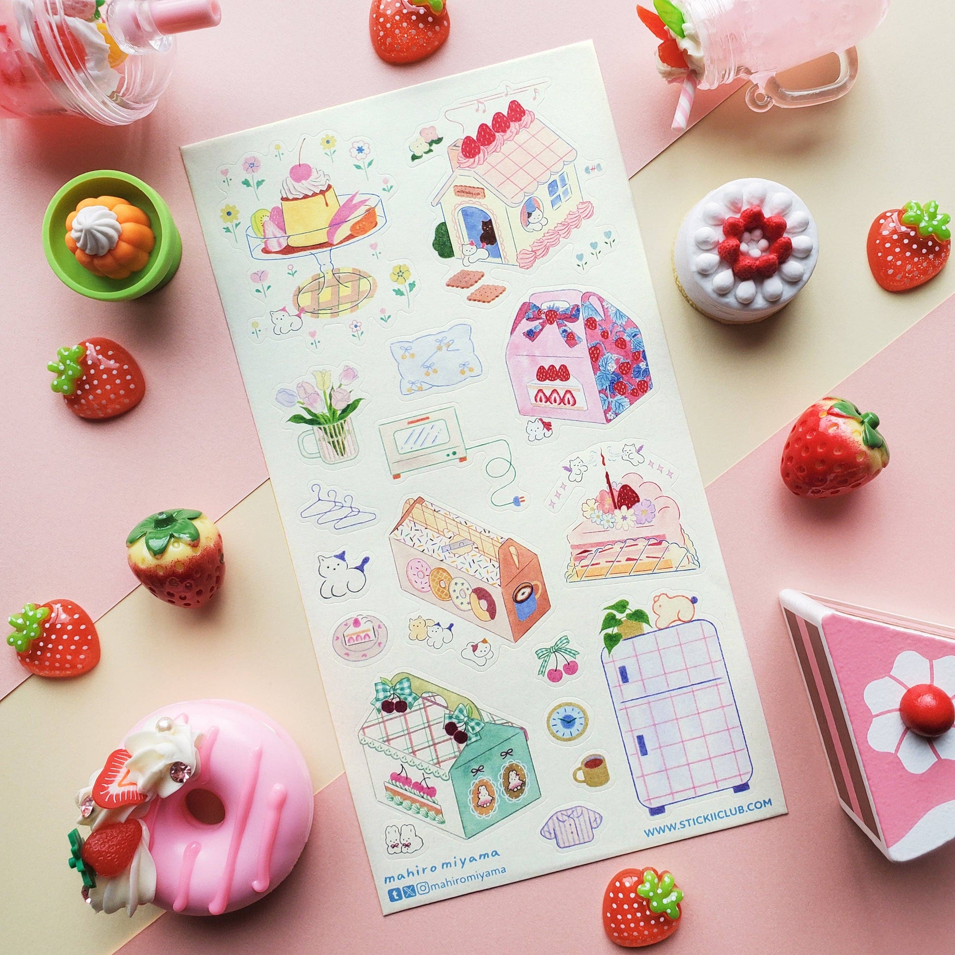 Sheet of colorful pastry stickers with various designs on a pink surface with decorative items.