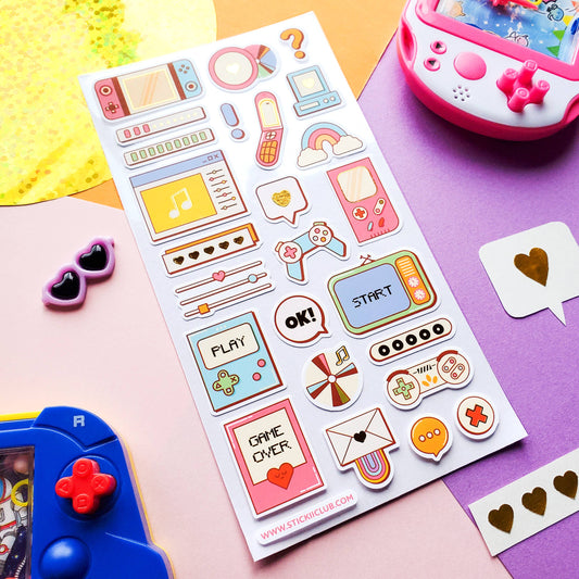 Sheet of colorful retro-themed stickers on a pink surface with gaming console and sunglasses.