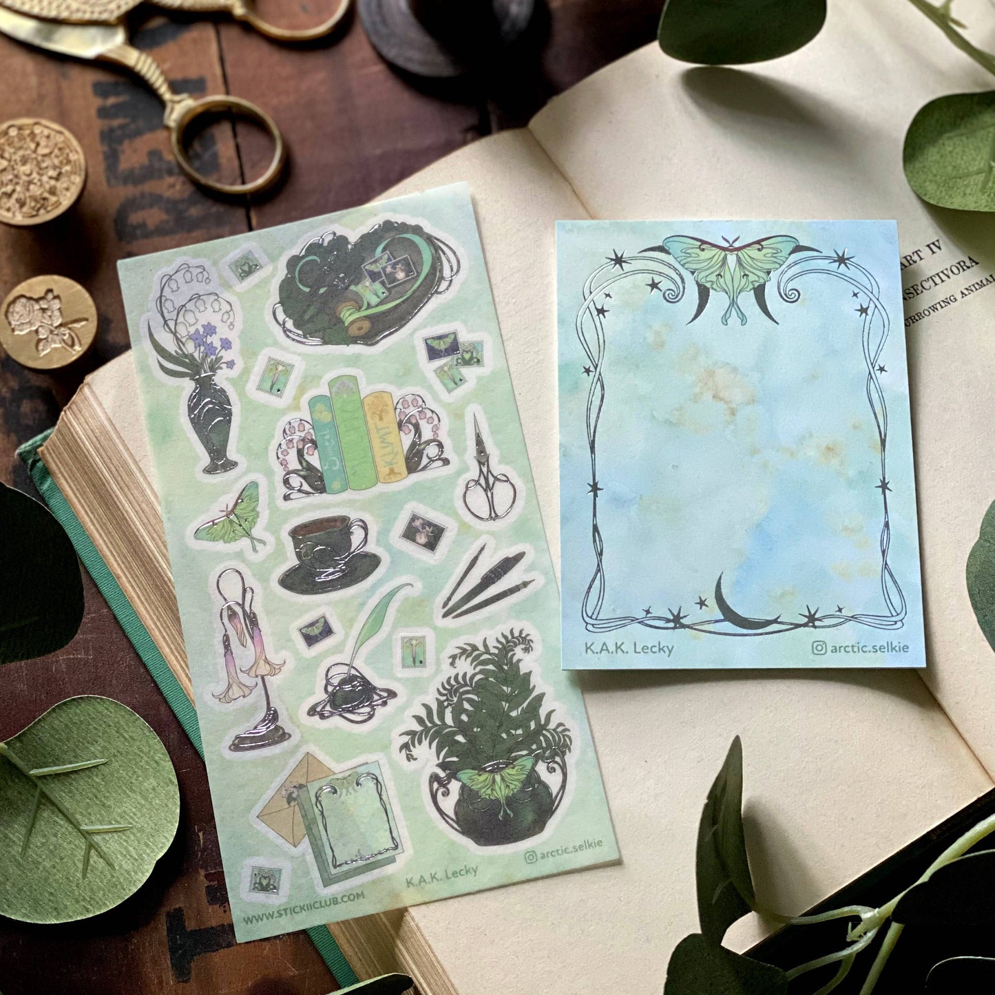Two sticker sheets on an open book with decorative elements.