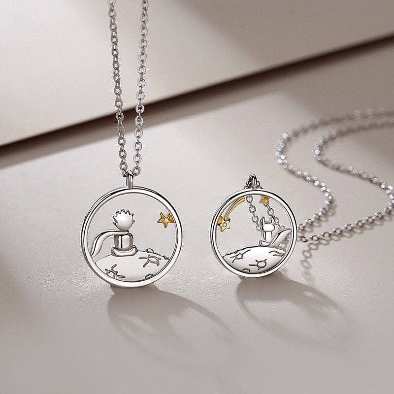 Two silver necklaces with circular pendants on a light surface