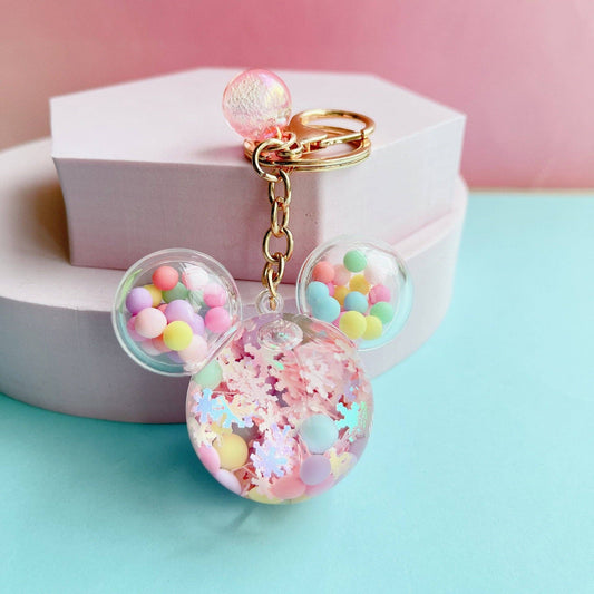 Colorful Mouse keychain with pastel beads and confetti on a pink and blue background