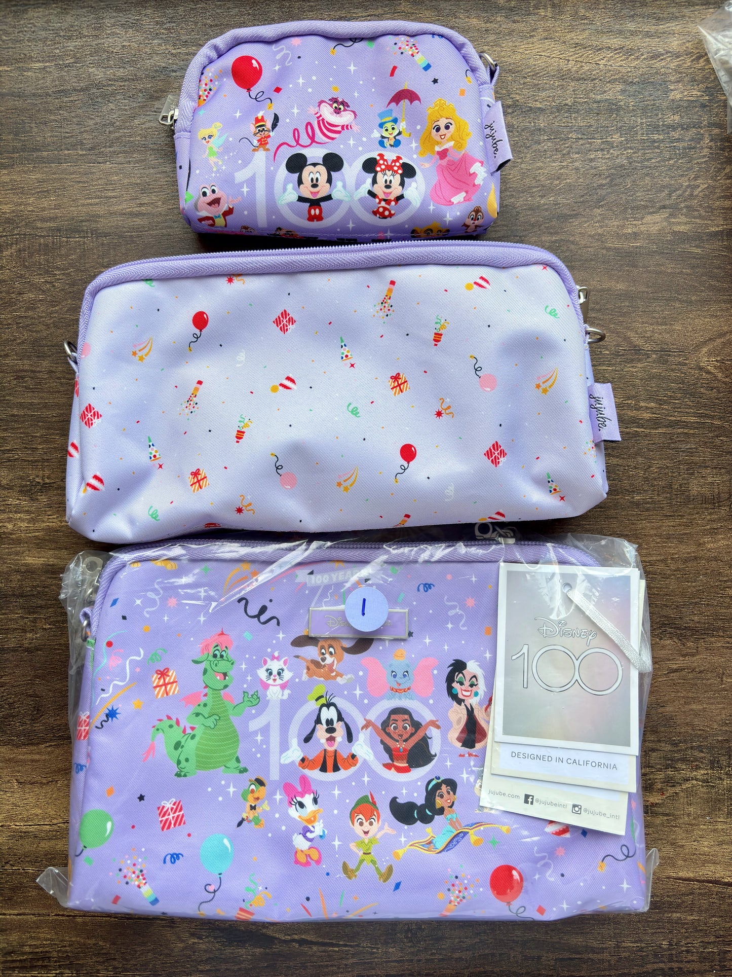 Three purple pouches with Disney cartoon character designs on a wooden surface.