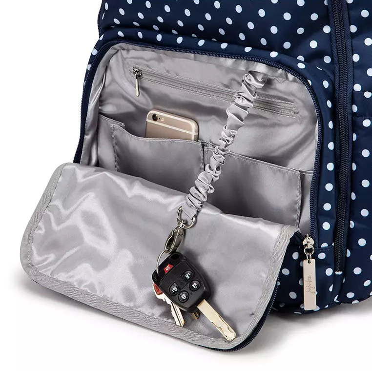 Navy polka dot backpack with interior pocket showing phone, keys, and earbuds.