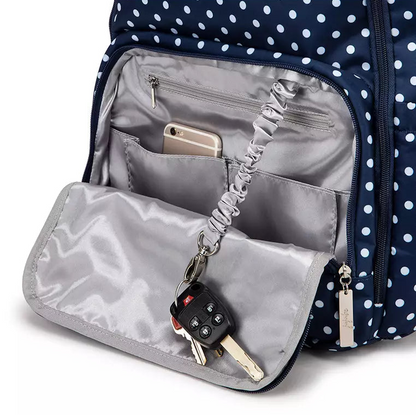 Navy polka dot backpack with interior pocket showing phone, keys, and earbuds.