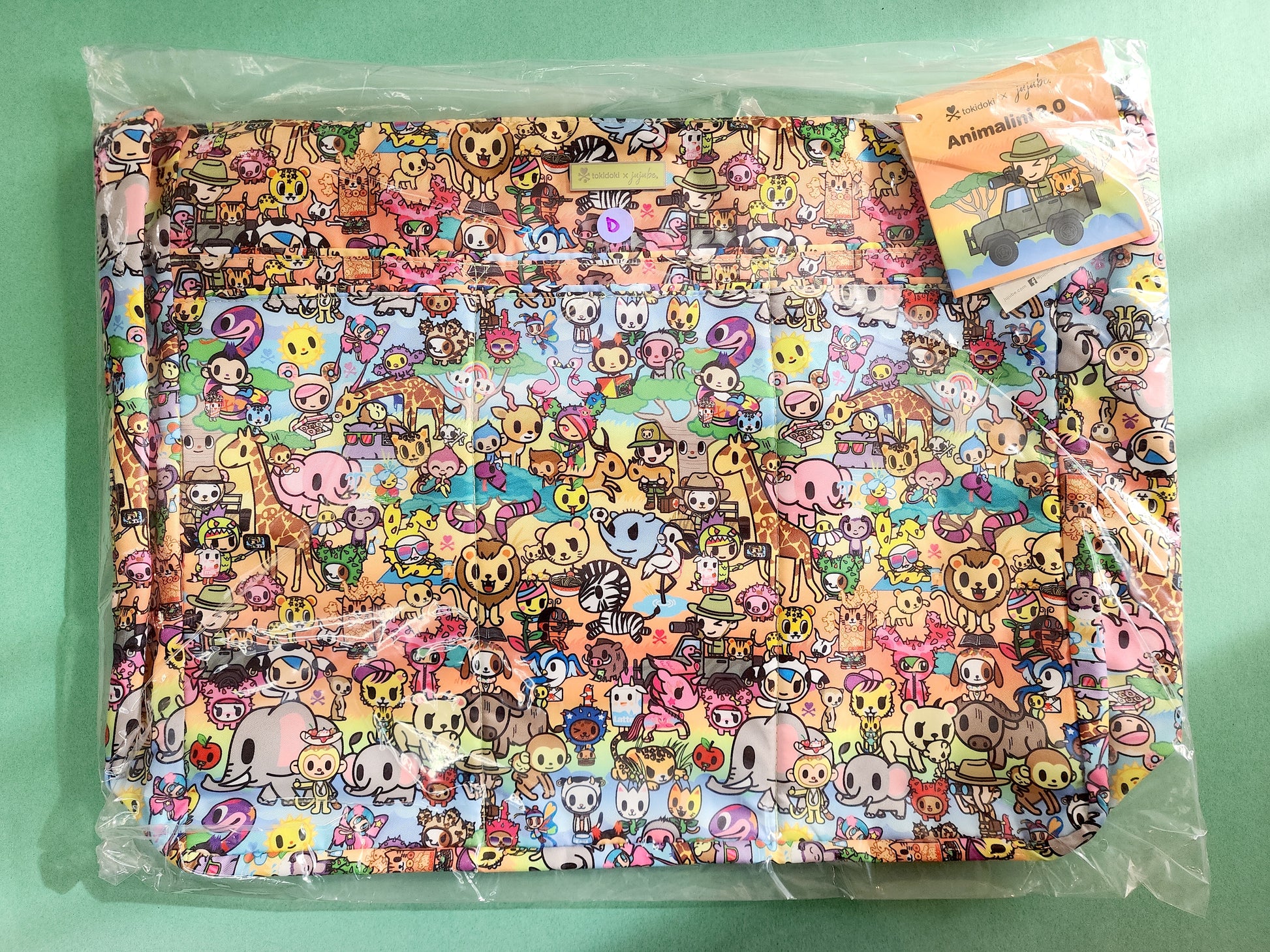 Colorful cartoon-patterned fabric in a clear package on a green background