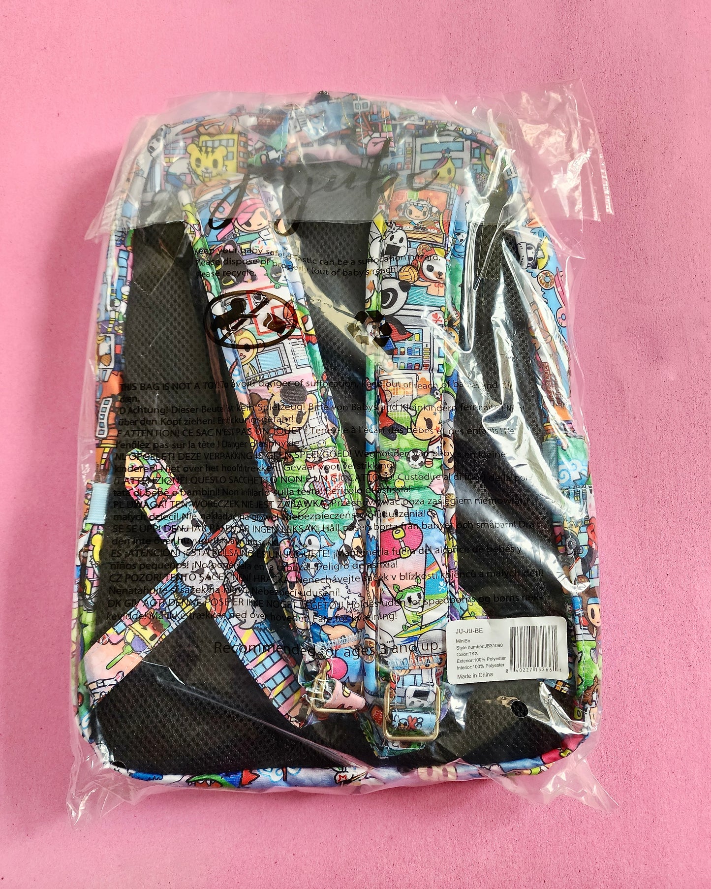 Colorful patterned backpack in clear packaging on a pink background