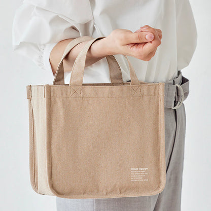 Person holding a beige tote bag with text on a white background