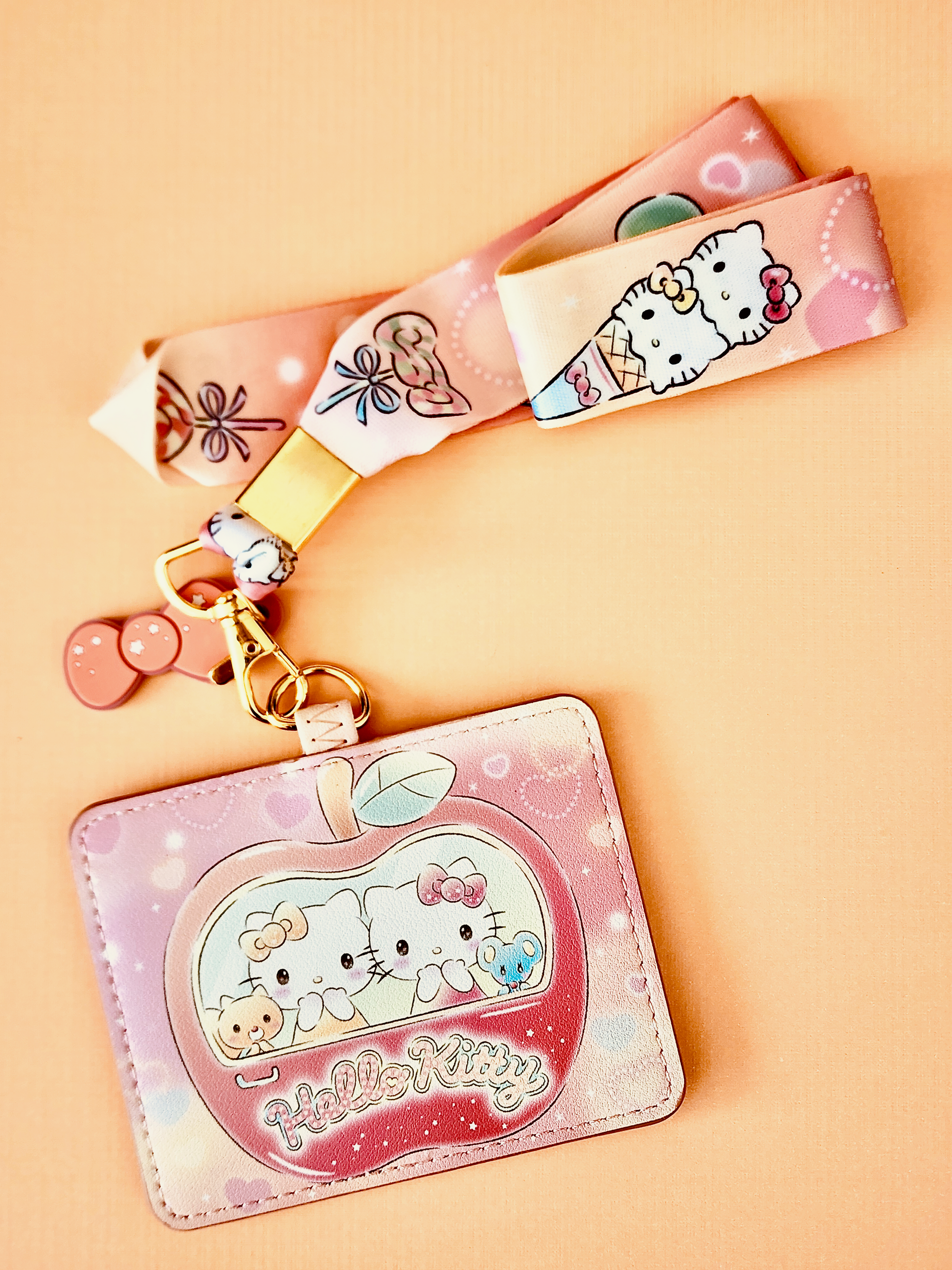 Pastel orange Hello Kitty-themed keychain on a beige background