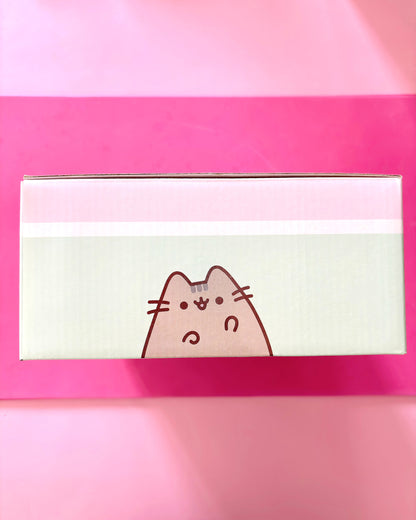 A rectangular product box featuring a cartoon cat face on a pale green front panel, photographed against a bright pink background.