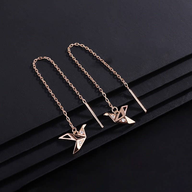 Two gold necklaces with origami crane pendants on a black background