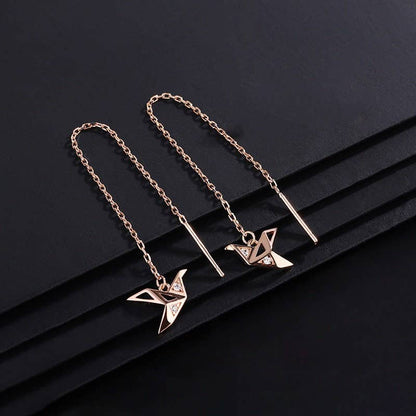 Two gold necklaces with origami crane pendants on a black background