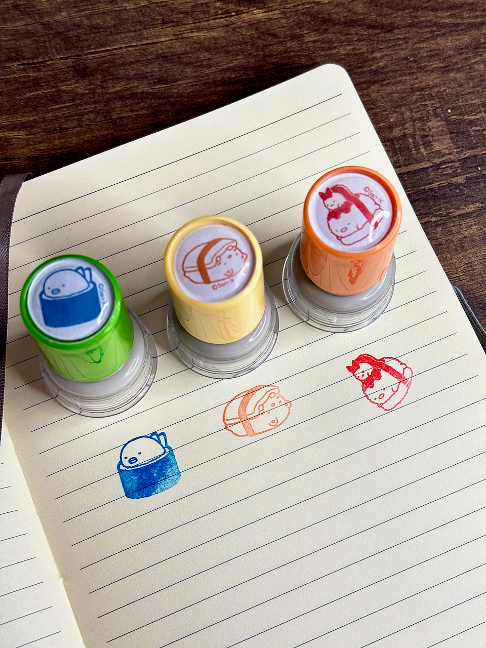 Four colorful rubber stamps on a lined notebook page with printed designs.