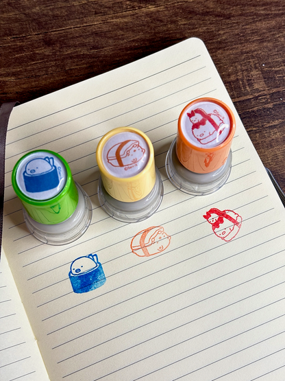 Four colorful rubber stamps on a lined notebook page with printed designs.