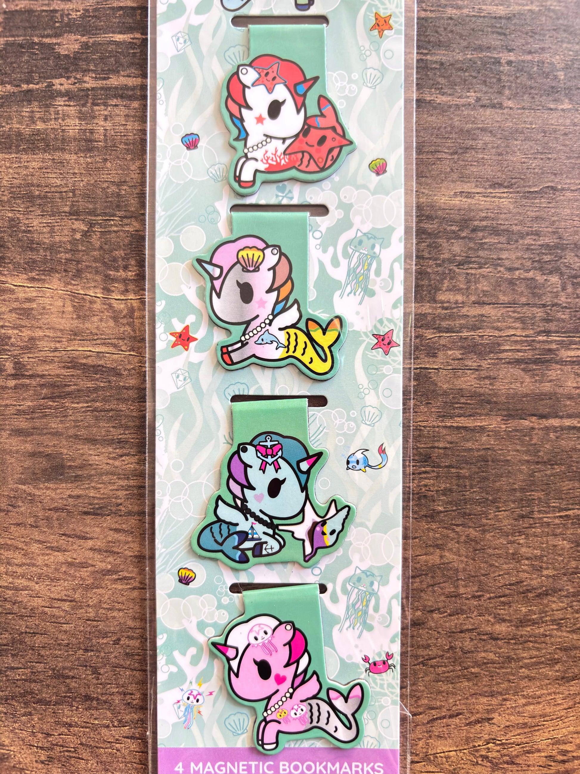Set of four colorful magnetic bookmarks with cartoon designs on a wooden surface