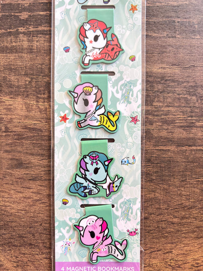 Set of four colorful magnetic bookmarks with cartoon designs on a wooden surface