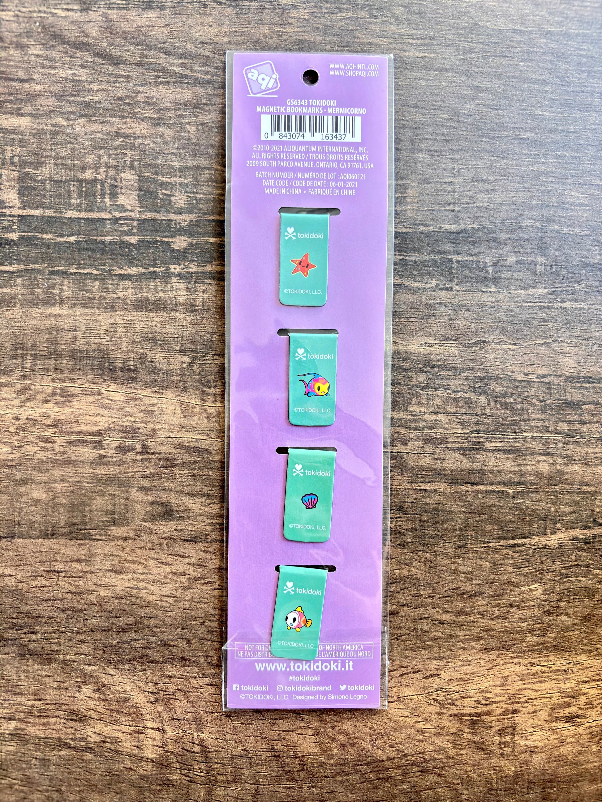back of packaging of four small green bookmarks with colorful designs on a purple background.