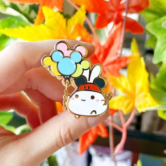 sum lil things character with mickey ears hat holding mouse head shaped pastel balloons